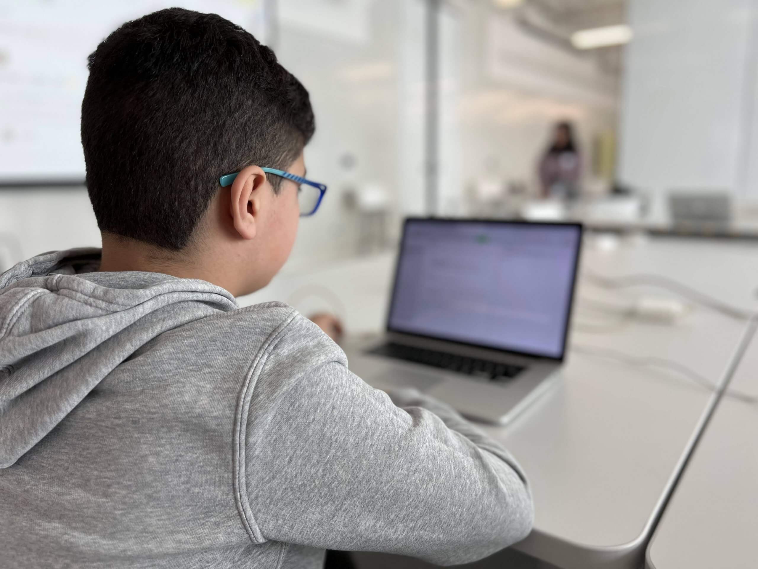 A young person looking at a laptop in a workshop