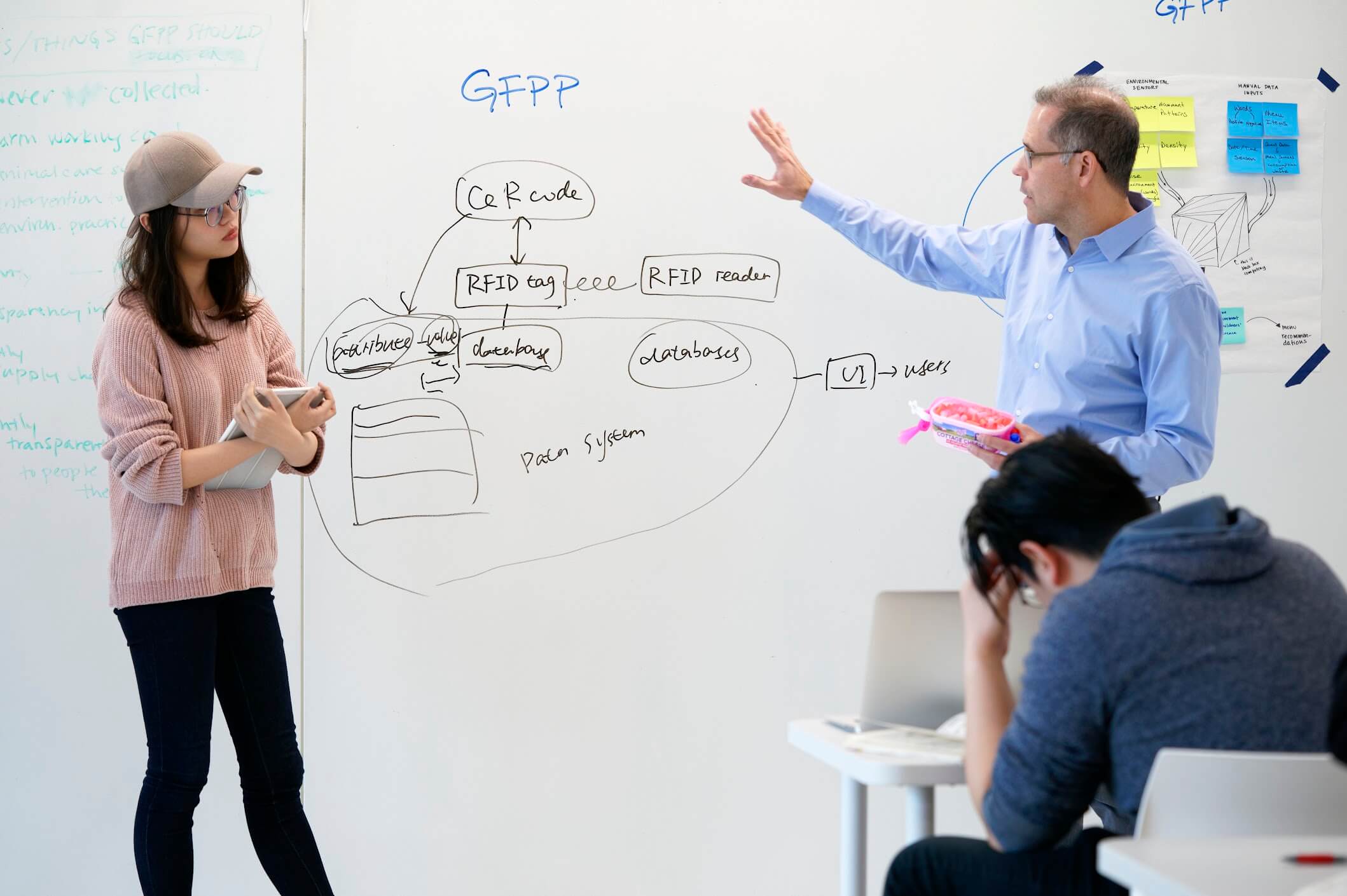 Carlos Teixeira presenting in front of a white board with a student.
